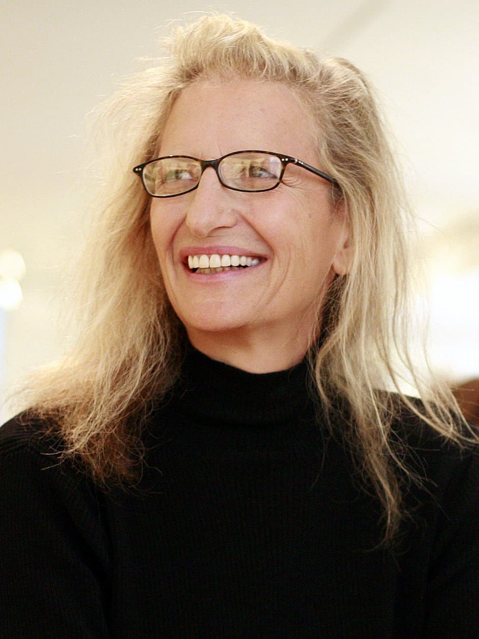 Annie Leibovitz, laughing, in glasses and a black top, with long fair hair.