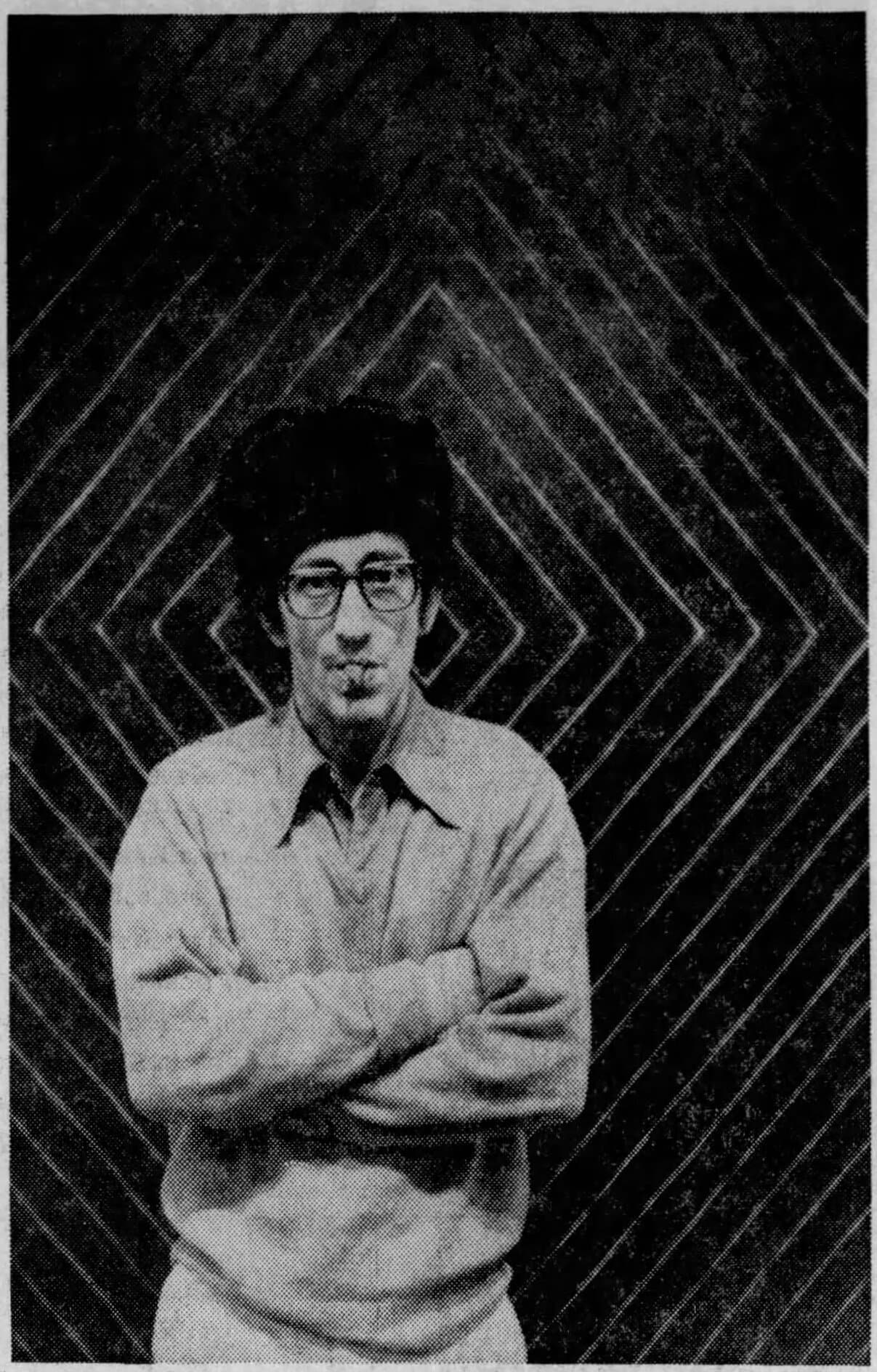Frank Stella in glasses, in front of one of his black stripe paintings.