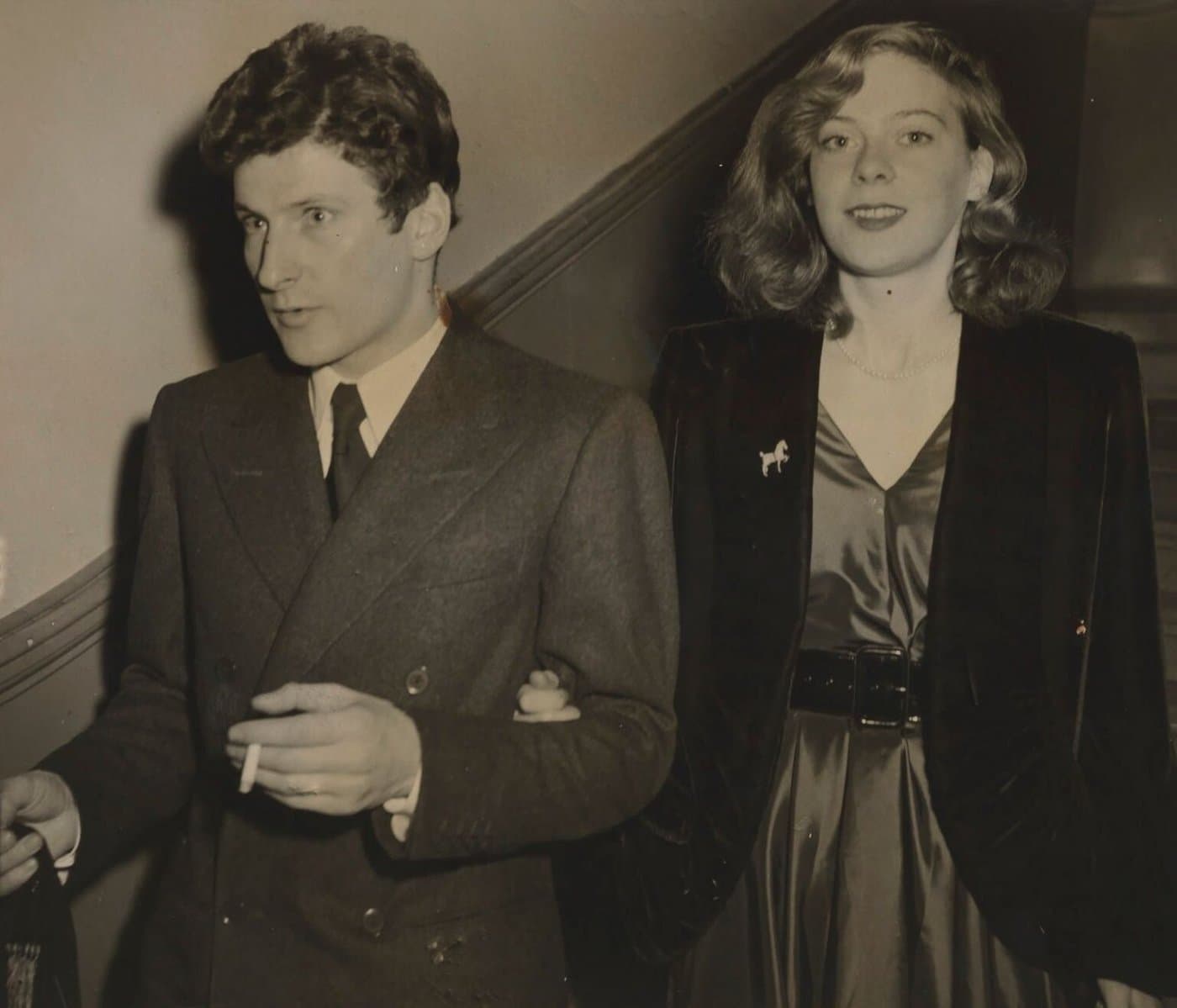 Lucian Freud in a suit, holding a cigarette, beside Lady Caroline Blackwood.