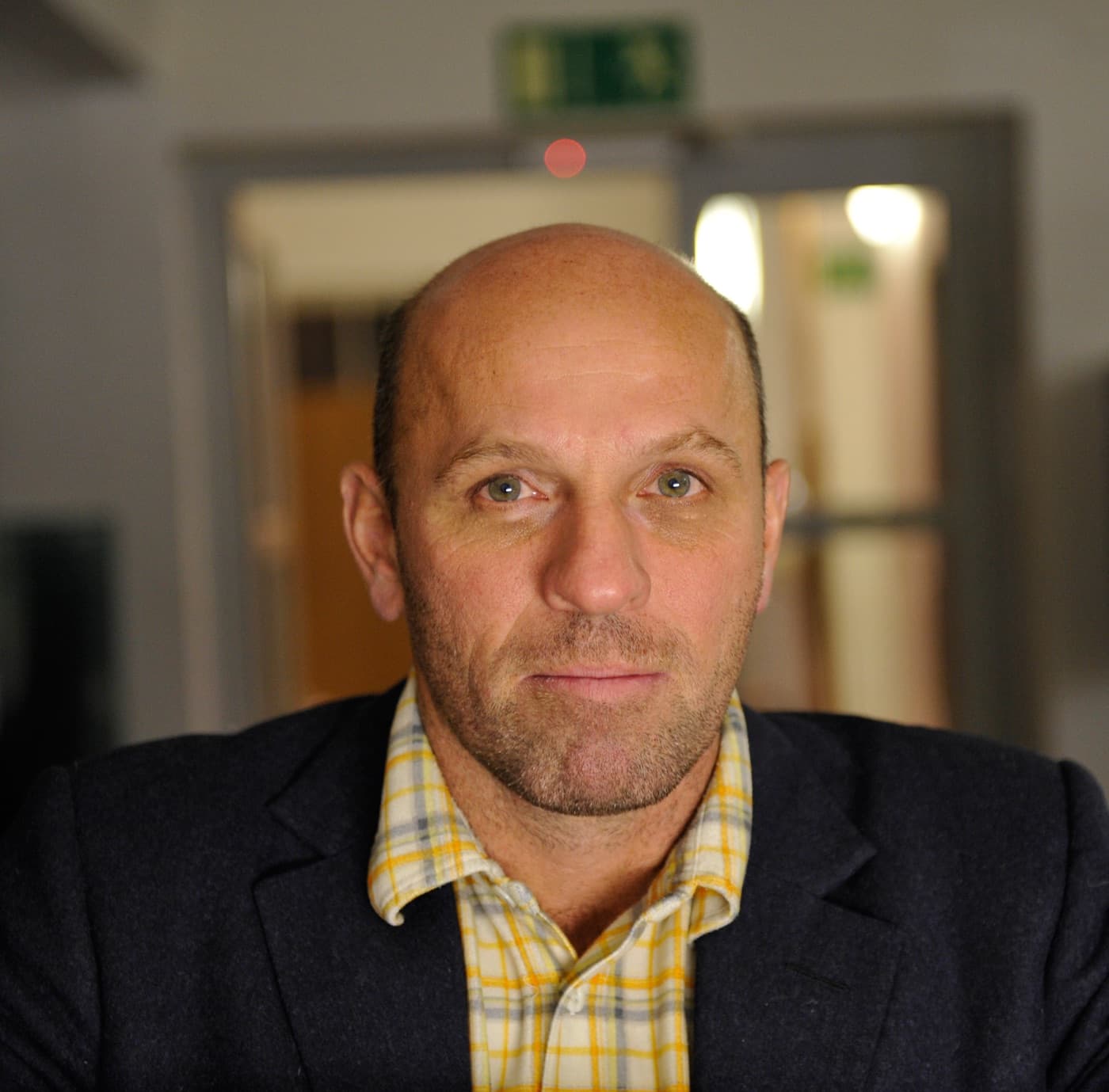 Peter Doig, with close-cropped hair, in a dark jacket and checked shirt.