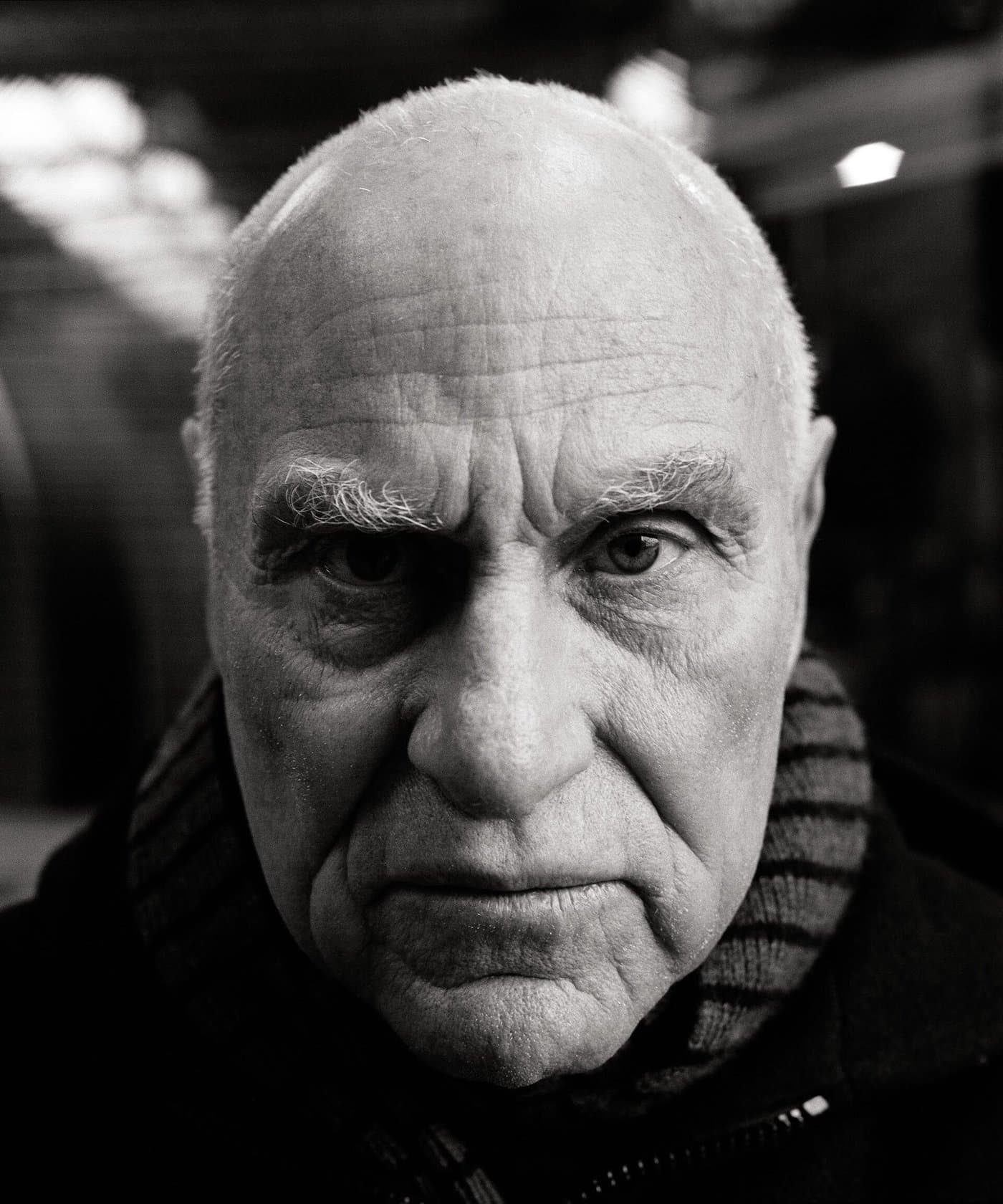 Richard Serra in close-up, bald, with a level stare.