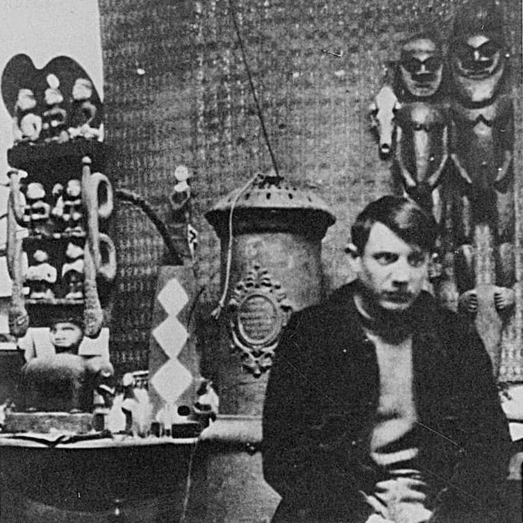 Pablo Picasso seated in his Bateau-Lavoir studio in Montmartre in 1908, surrounded by the African and Oceanic sculpture he had begun collecting