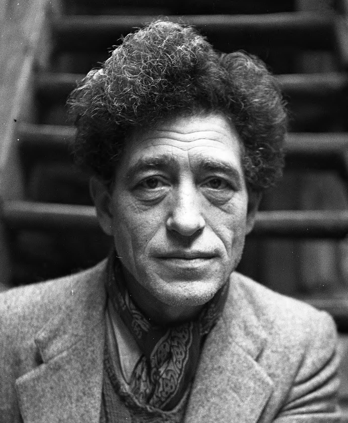 Alberto Giacometti with thick curly hair, looking straight at the camera.