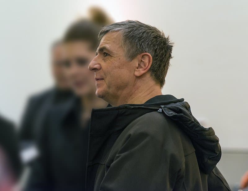 Andreas Gursky in profile, in a dark jacket, among visitors at a museum.