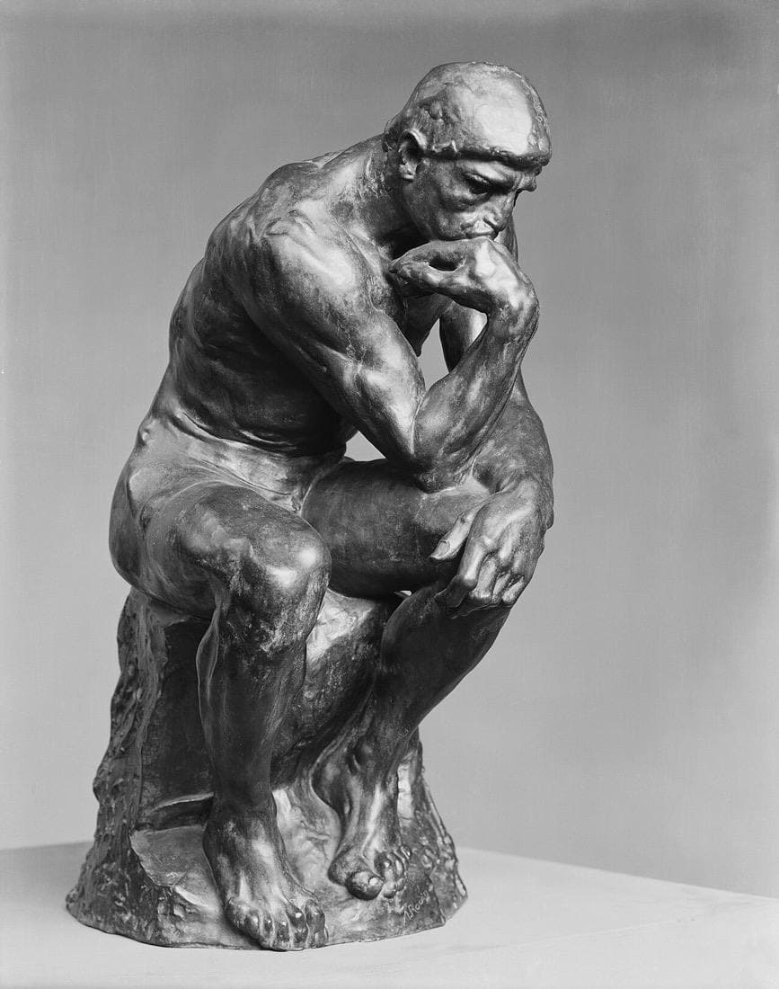Rodin's The Thinker: a seated bronze figure leaning forward with his chin resting on his hand.
