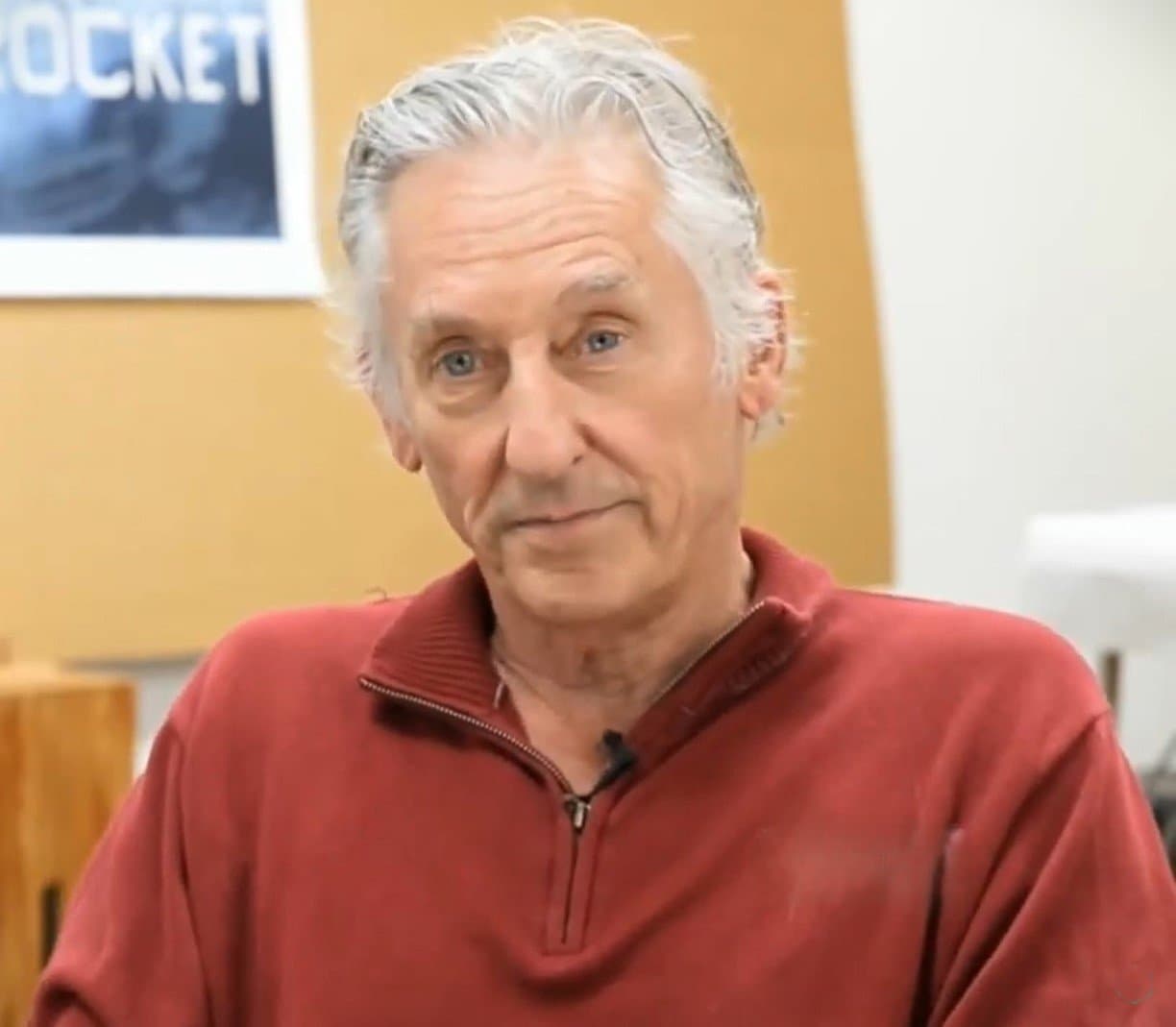 Ed Ruscha with swept-back grey hair, in a red sweater.