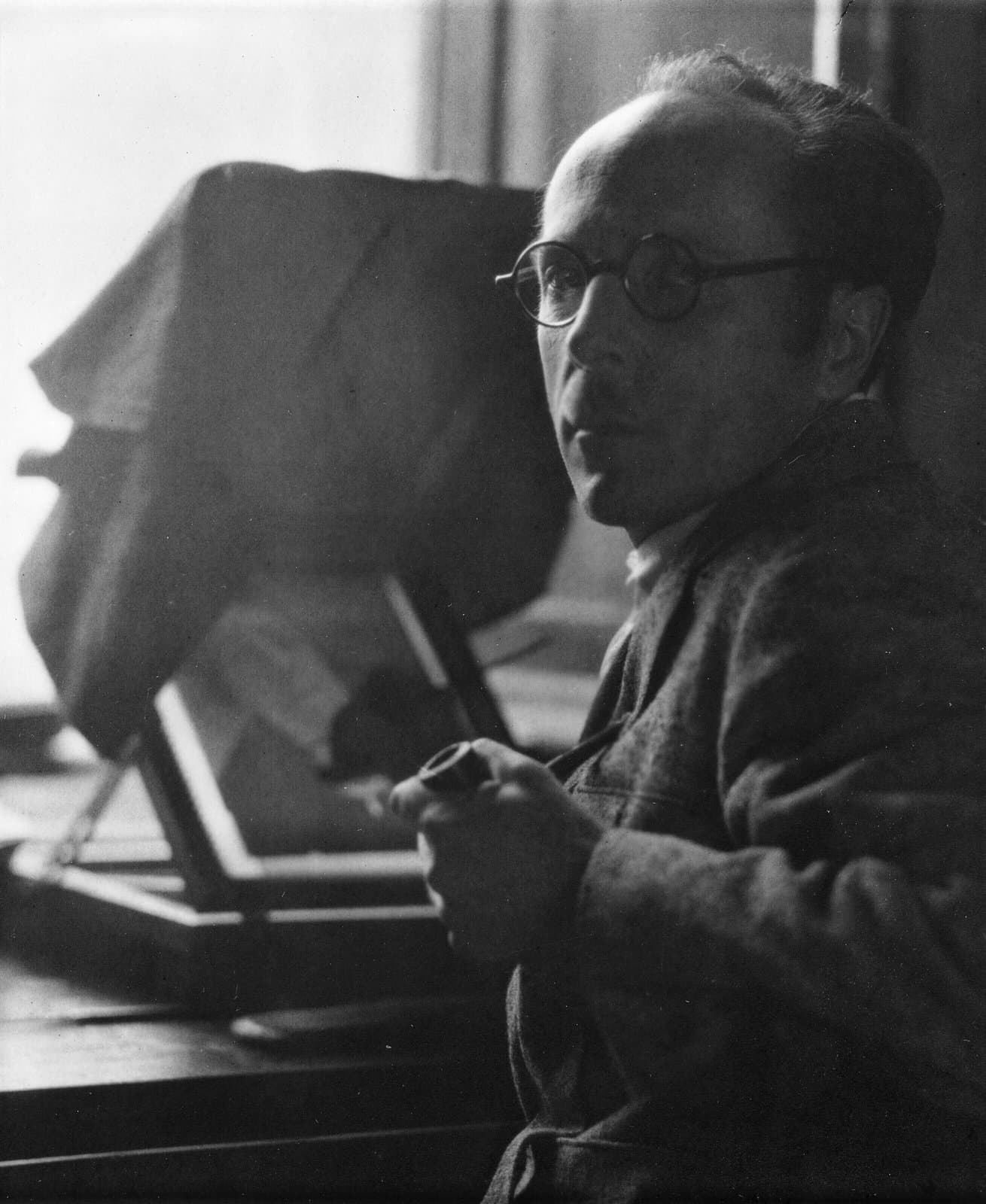 Edward Weston in round glasses beside a large camera, in a black and white self-portrait