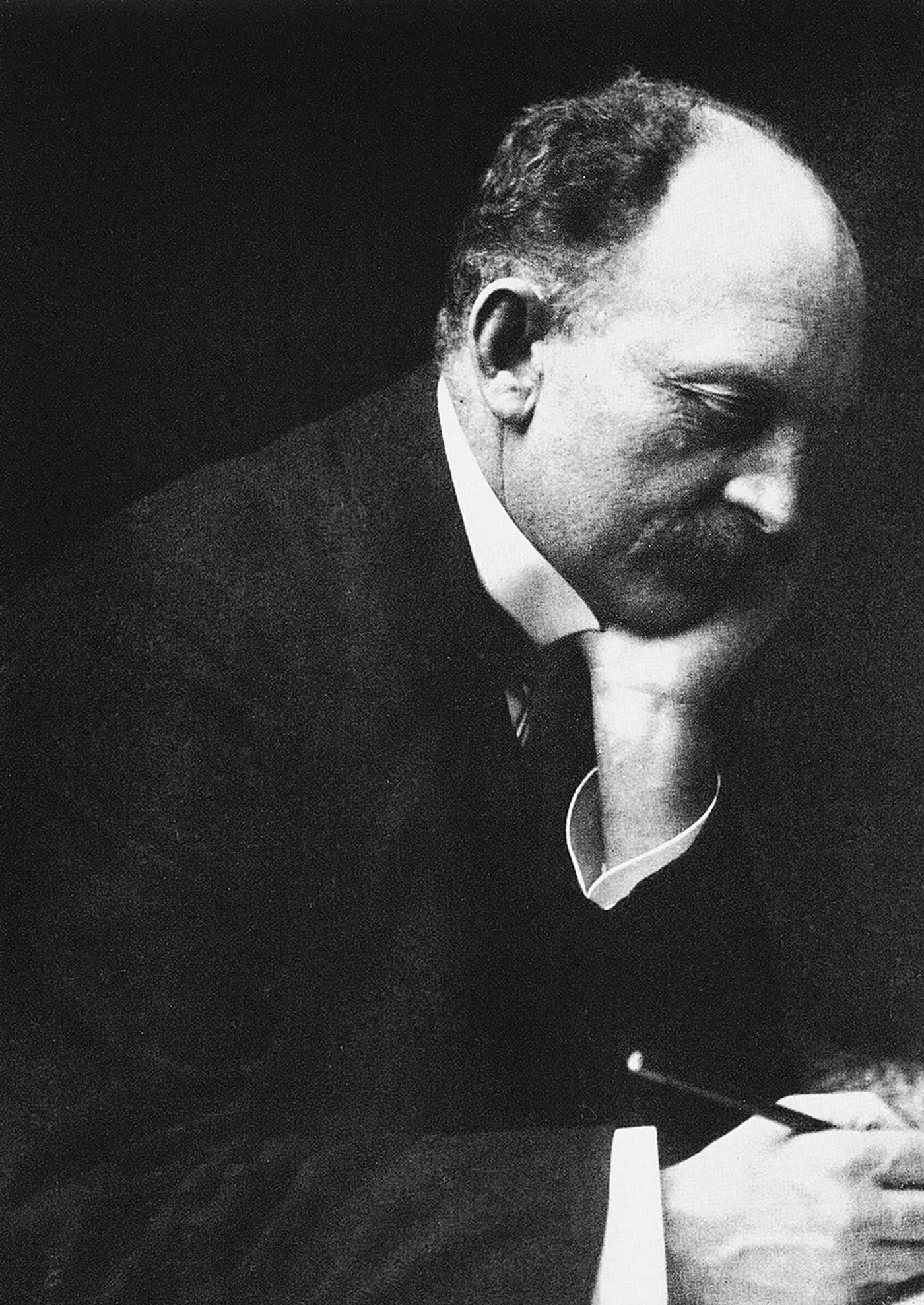 Emil Nolde, head bowed and resting on his hand, in a dark jacket.