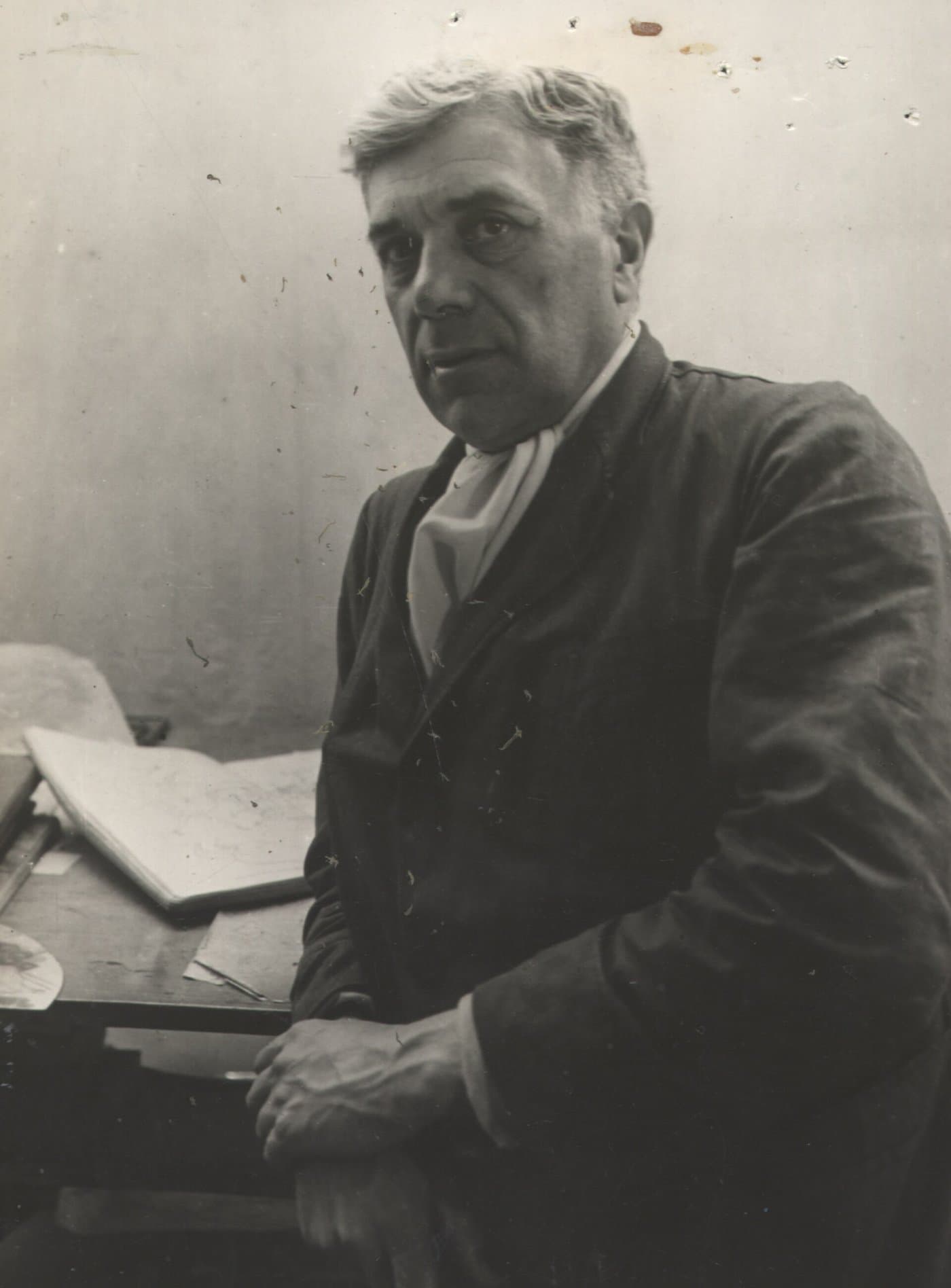 Georges Braque in a work jacket, seated, looking to the side.