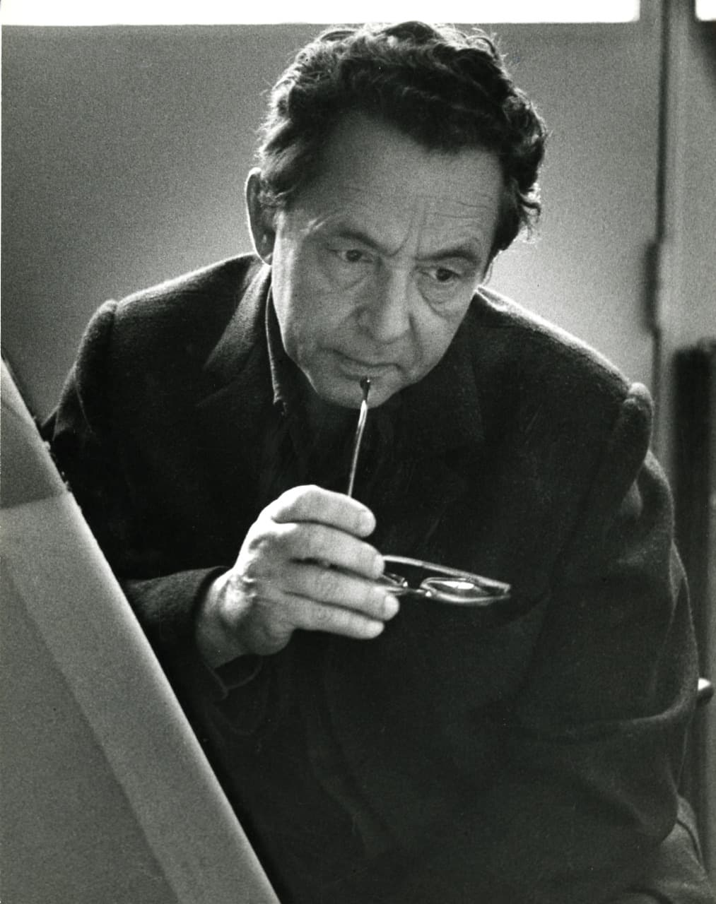 Hans Hartung holding his glasses to his mouth, in black and white.
