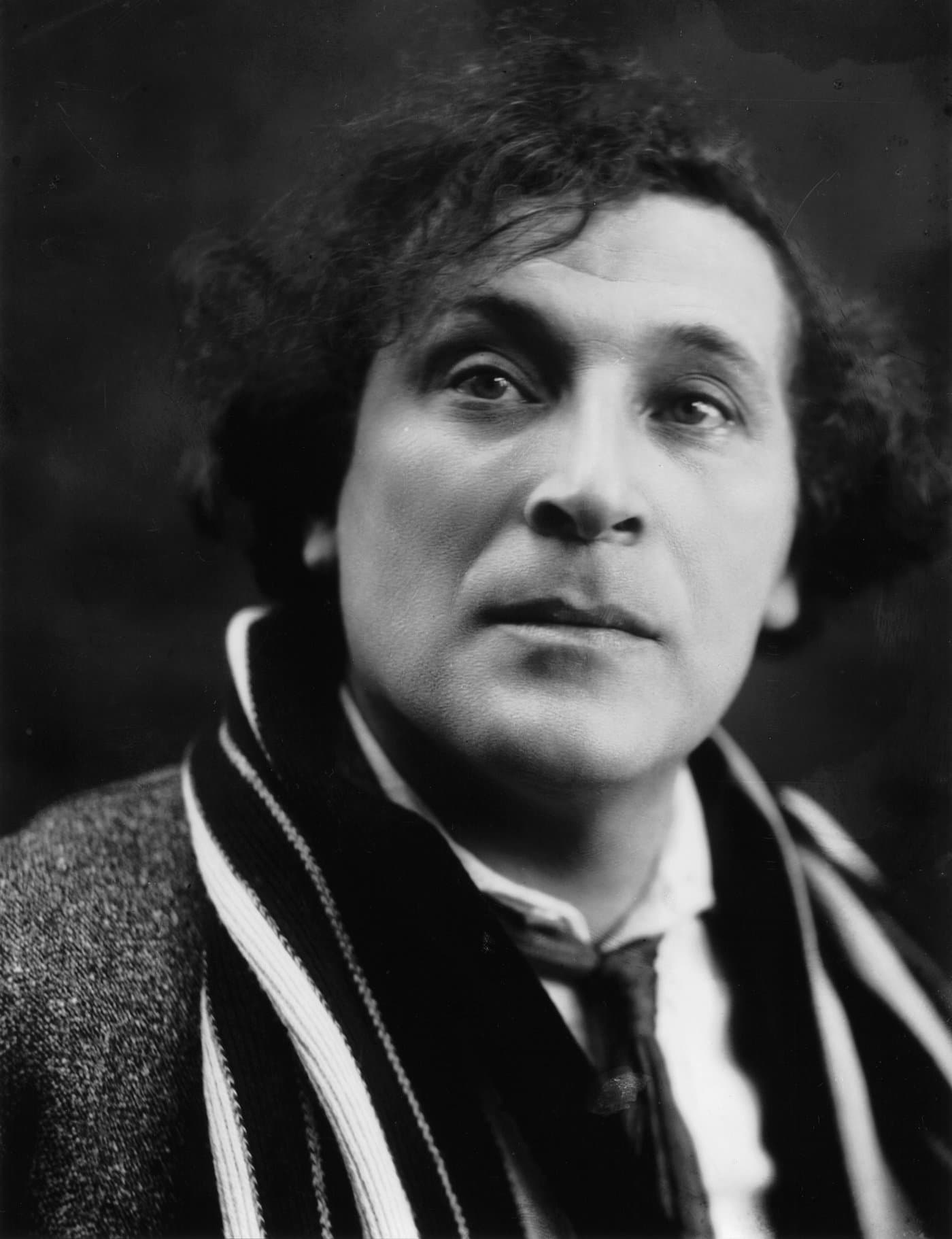 Marc Chagall, close up, with a mass of curly hair, gazing to one side.