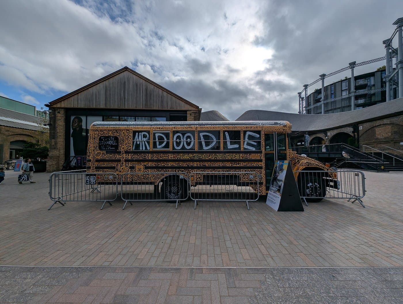 A school bus covered in Mr Doodle's black and white doodles, parked on a London square.