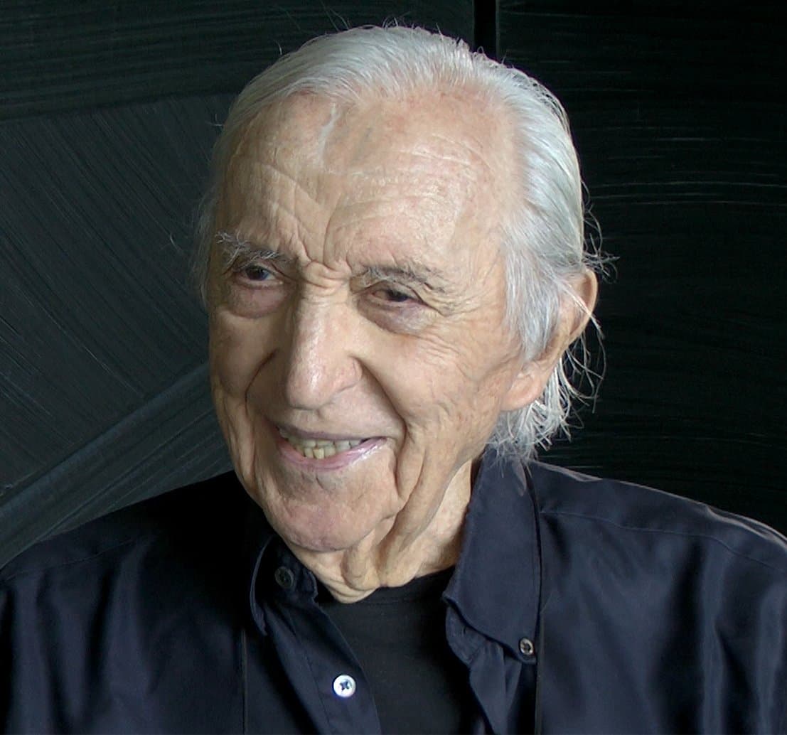 Pierre Soulages, white-haired, smiling, in a dark shirt.