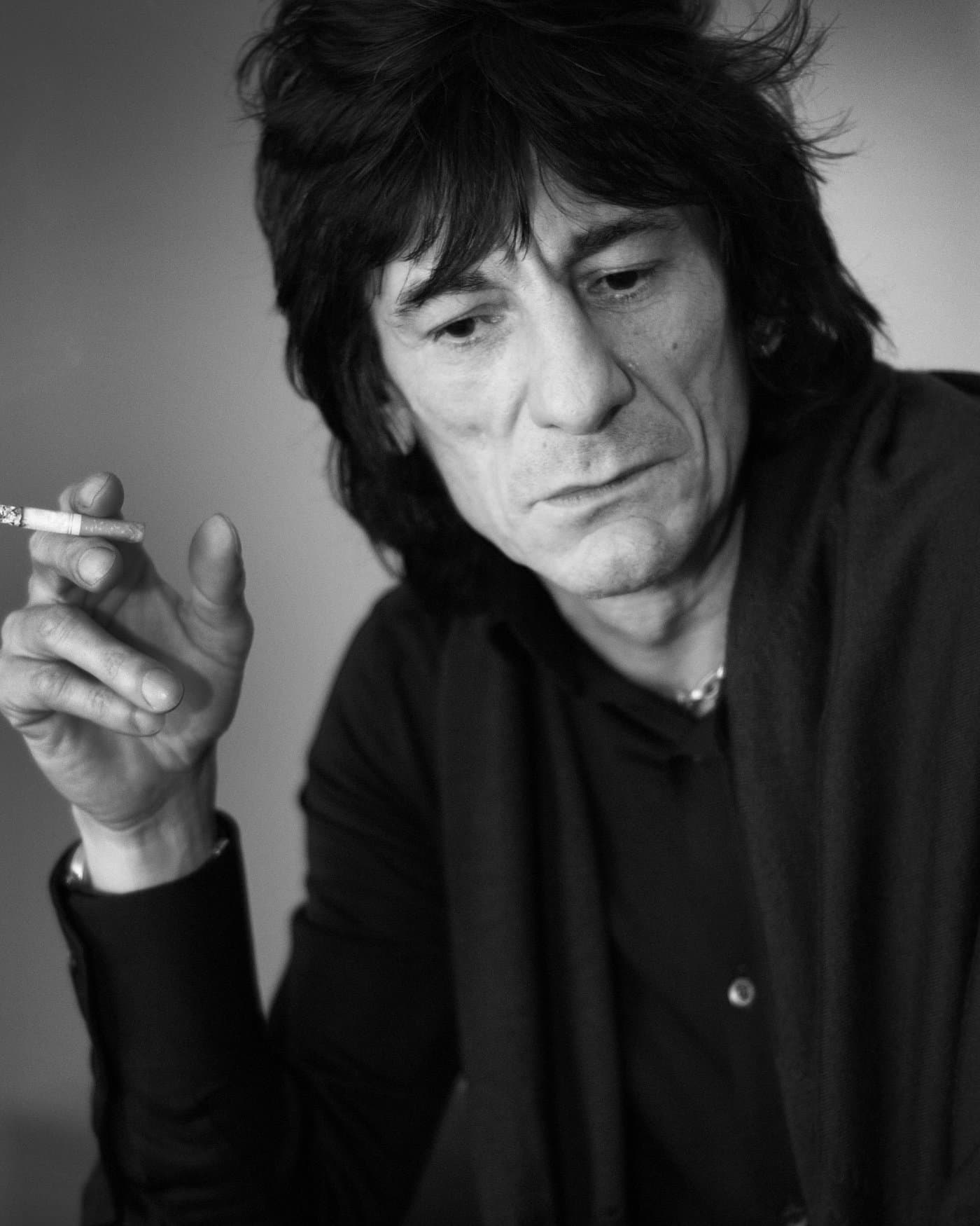 Ronnie Wood with dark spiky hair, holding a cigarette.