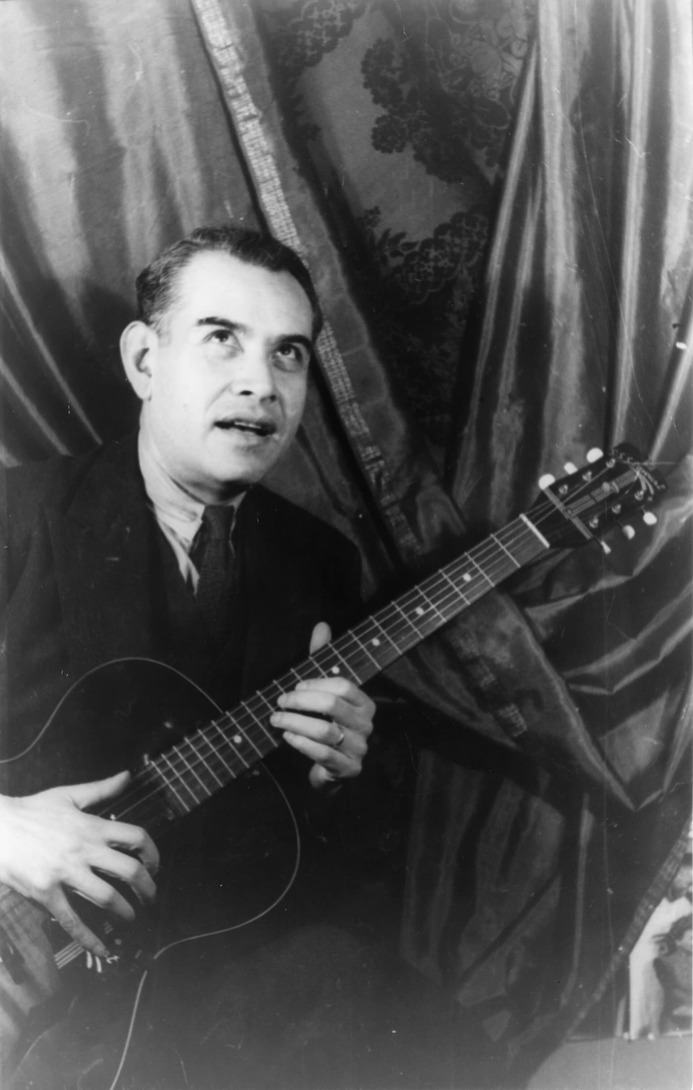 Rufino Tamayo with a guitar, looking up, in black and white.