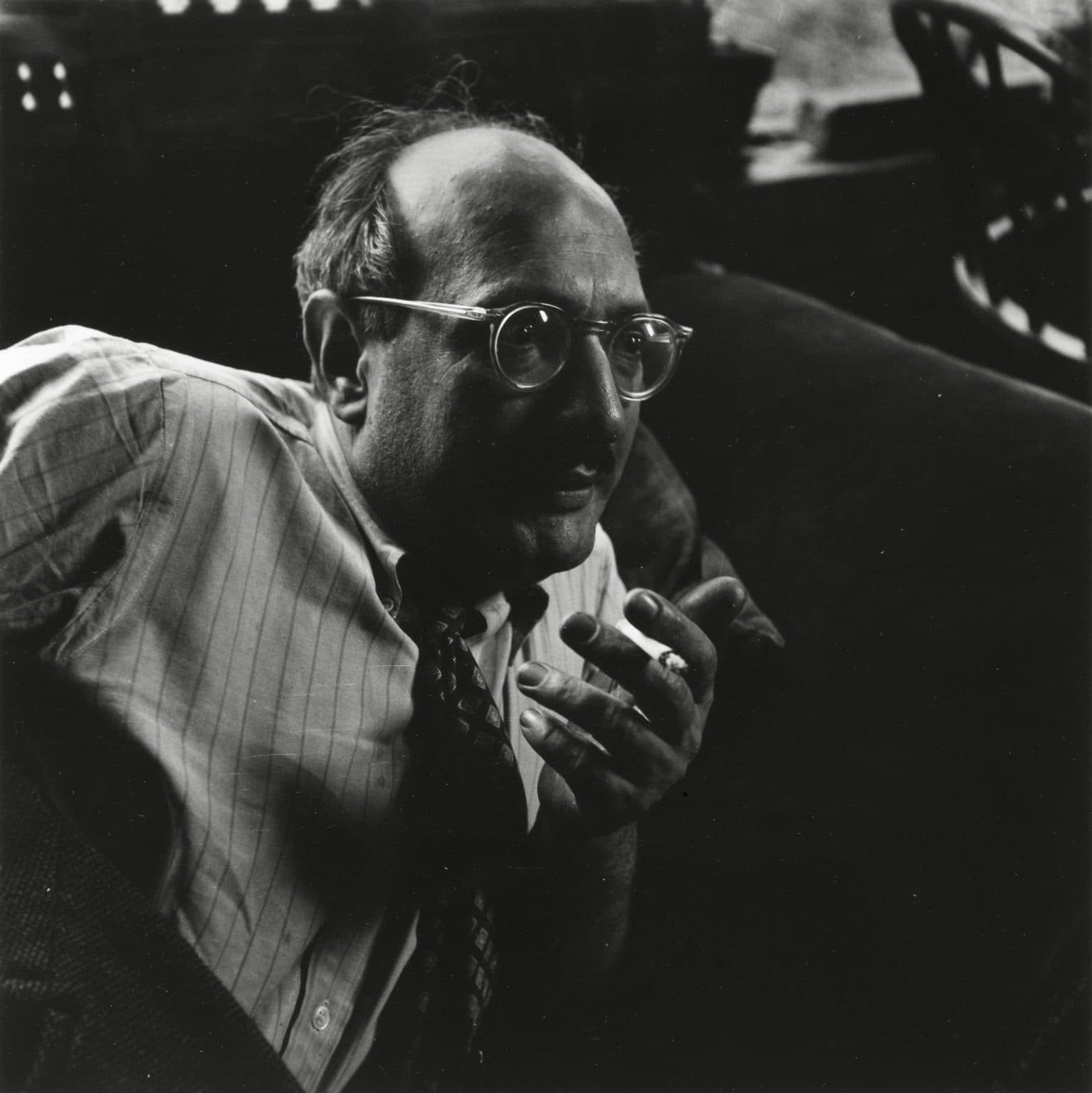 Mark Rothko, in glasses and a striped shirt, leaning back with a cigarette in his hand, in a black-and-white photograph of about 1949.