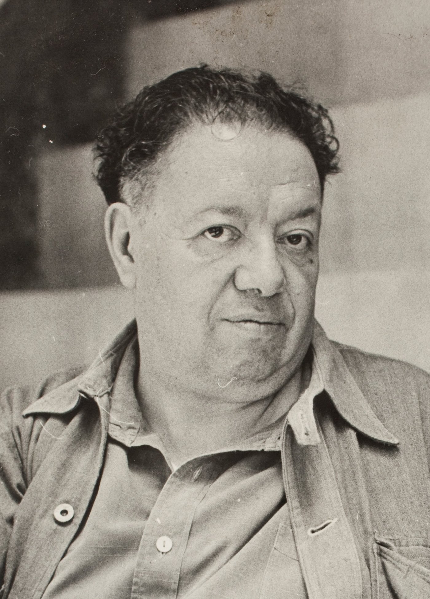 Diego Rivera, head and shoulders, with dark curly hair, half smiling.