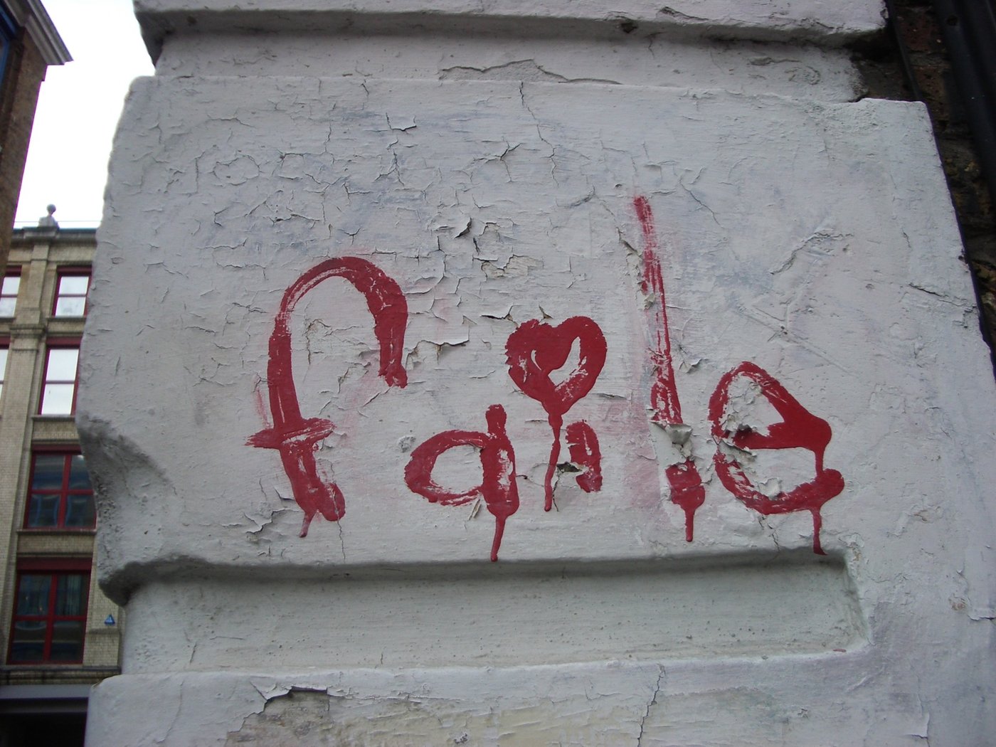 FAILE painted in red on a white wall, with a heart in place of the I.