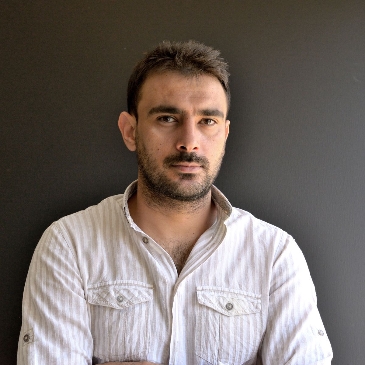 Mehdi Ghadyanloo in a white shirt against a dark grey background.