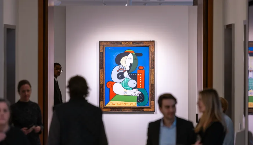 Visitors talking in front of a framed Picasso hung alone on a white gallery wall at a pre-sale view